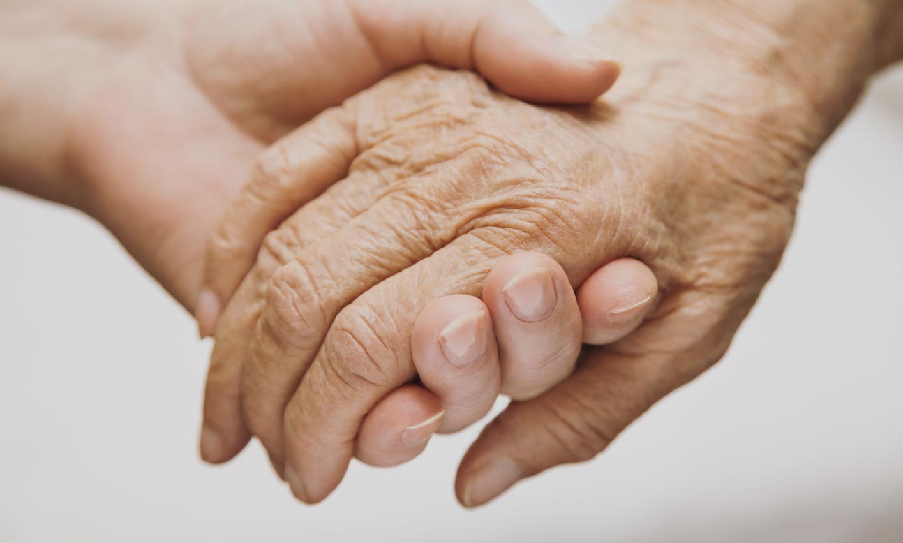 Caring hand holding hand of senior.